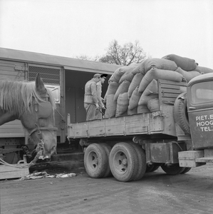 167050 Afbeelding van het overladen van zakken graan van vrachtauto naar goederenwagens van de N.S. te Amersfoort.